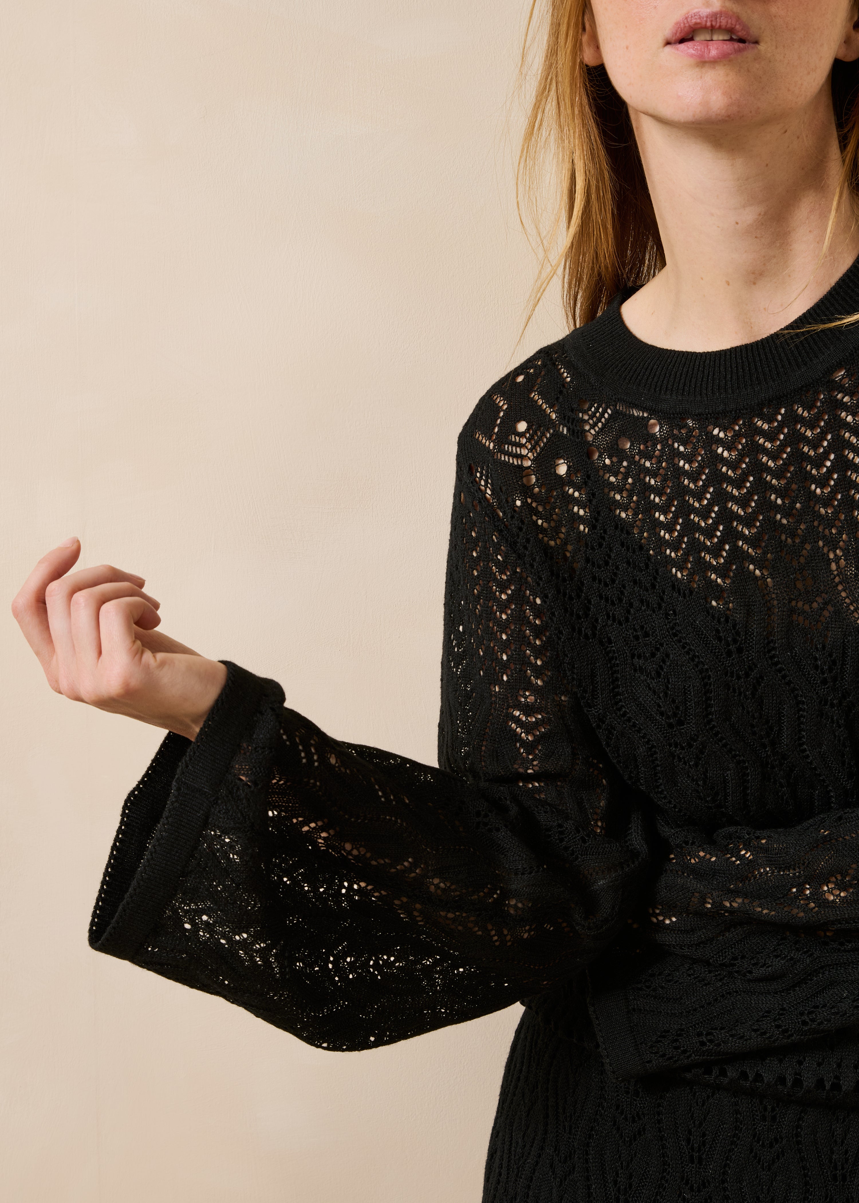 Schwarzes, figurbetontes Kleid aus durchbrochenem Strick mit langen Ärmeln